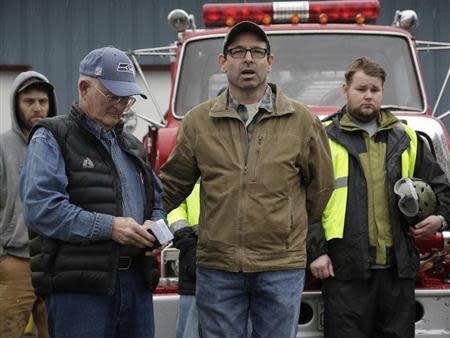 Darrington Mayor Dan Rankin (2nd R) and Pastor Mike De Luca (2nd L) lead workers and community members in prayer and a moment of silence marking the one-week anniversary of the Oso landslide at the fire station in Darrington, Washington March 29, 2014. REUTERS/Jason Redmond