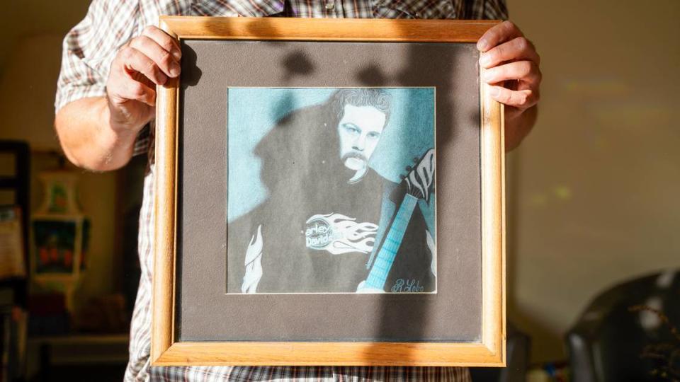 Luke, an Arroyo Grande resident who recently moved into a permanent home using a housing choice voucher, holds one of the pieces of artwork in his home he kept from before he became homeless in 2019.