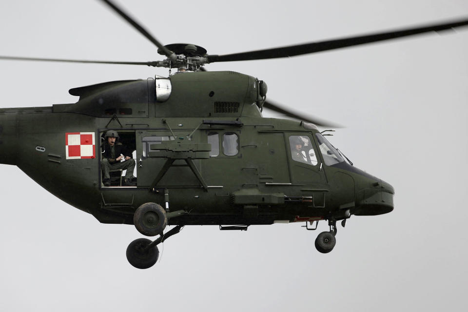 A Polish military helicopter fly over a group of migrants from the Middle East and elsewhere gathering at the Belarus-Poland border near Grodno, Belarus, Monday, Nov. 8, 2021. Poland increased security at its border with Belarus, on the European Union's eastern border, after a large group of migrants in Belarus appeared to be congregating at a crossing point, officials said Monday. The development appeared to signal an escalation of a crisis that has being going on for months in which the autocratic regime of Belarus has encouraged migrants from the Middle East and elsewhere to illegally enter the European Union, at first through Lithuania and Latvia and now primarily through Poland. (Leonid Shcheglov/BelTA via AP)