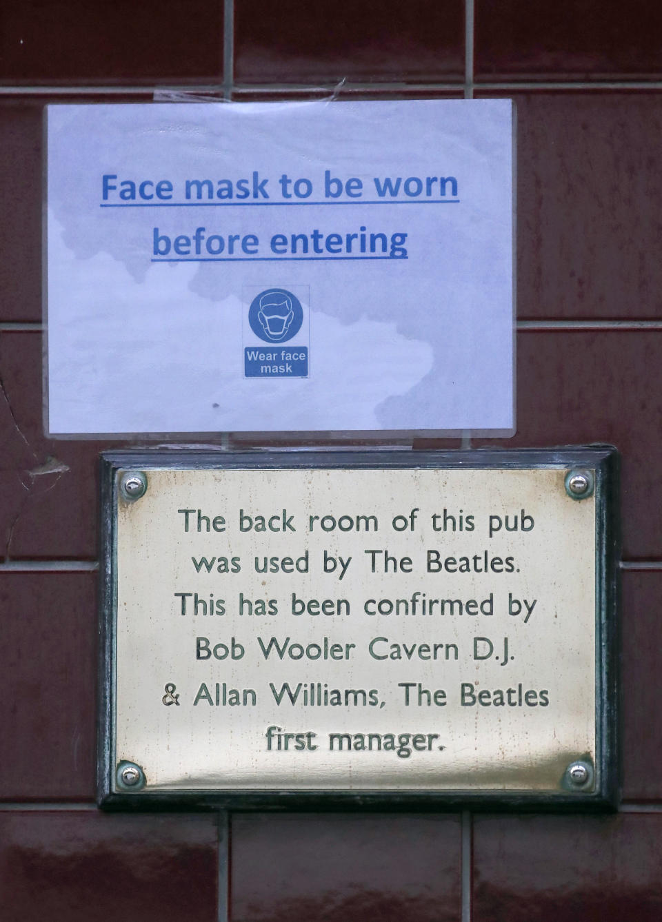 A sign at the entrance of a pub demands wearing a face mask as new measures across the region are set to come into force in Liverpool, England, Wednesday, Oct. 14, 2020. New plans unveiled this week show Liverpool is in the highest-risk category, and its pubs, gyms and betting shops have been shut.(AP Photo/Frank Augstein)