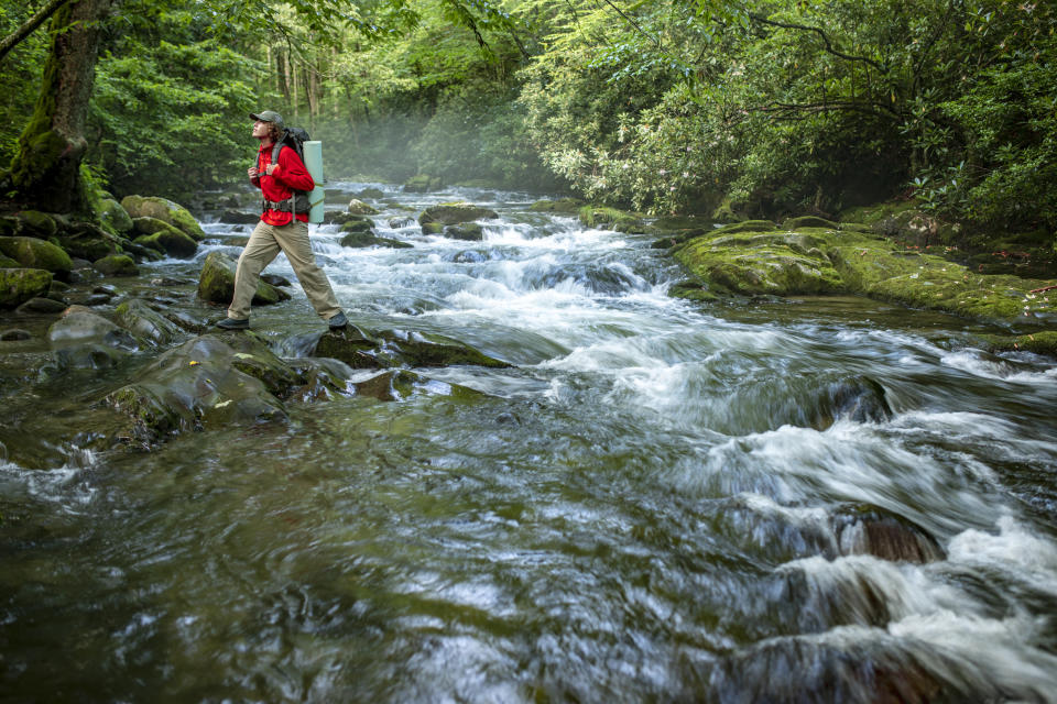 A hiker walks over the boulders that dot the roaring river in Great Smoky Mountains national park.