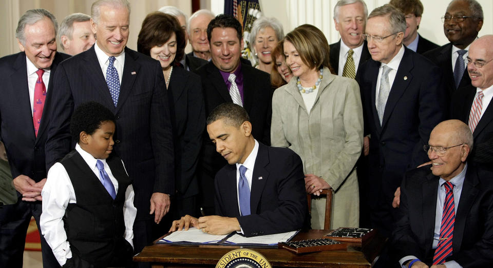 FILE - In this March 23, 2010 file photo, President Barack Obama signs the Affordable Care Act in the East Room of the White House in Washington. If Obama's health care law survives Supreme Court scrutiny, it will be nearly a decade before all its major pieces are in place. The law's carefully orchestrated phase-in is evidence of what's at stake in the Supreme Court deliberations that start March 26, 2012. With Obama are Marcelas Owens of Seattle, left, and Rep. John Dingell, D-Mich., right; from top left are Sen. Tom Harkin, D-Iowa., Senate Majority Whip Richard Durbin of Ill., Vice President Joe Biden, Vicki Kennedy, widow of Sen. Ted Kennedy, Sen. Christopher Dodd, D-Conn., Rep. Sander Levin, D-Mich., Ryan Smith of Turlock, Calif., Health and Human Services Secretary Kathleen Sebelius, House Speaker Nancy Pelosi of Calif., House Majority Leader Steny Hoyer of Md., Senate Majority Leader Harry Reid of Nev., Rep. Patrick Kennedy, D-R.I., House Majority Whip James Clyburn of S.C., and Rep. Henry Waxman, D-Calif. (AP Photo/J. Scott Applewhite, File)