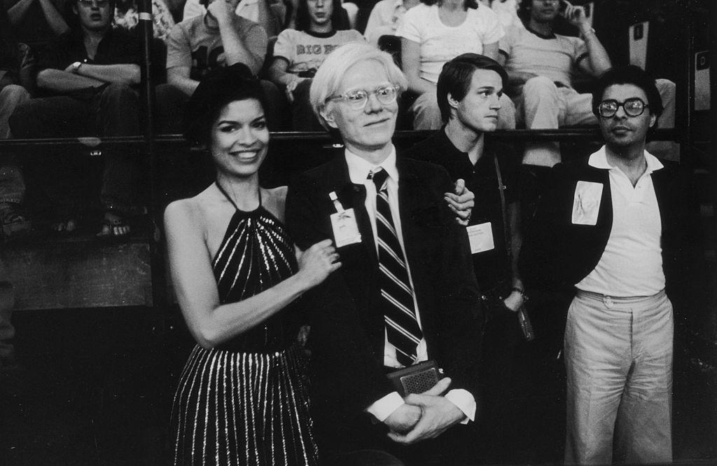 American artist Andy Warhol with Bianca Jagger in the audience at a the Rolling Stones concert during the band's 1975 Tour of the Americas.