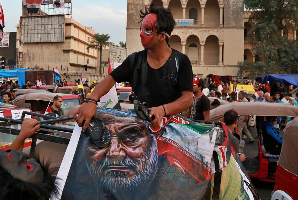 FILE - In this Nov. 3, 2019, file photo, a protester hits a poster showing the leader of the Iranian Revolutionary Guard's foreign wing, or Quds Force, Gen. Qassem Soleimani, who was killed in Iraq in a U.S. drone attack, with a shoe during protests in Baghdad, Iraq. Iran has had its fingers in Iraq's politics for years, but the U.S. killing of an Iranian general and Iraqi militia commander outside Baghdad has added new impetus to the effort, stoking anti-Americanism that Tehran now hopes it can exploit to help realize the goal of getting U.S. troops out of the country. (AP Photo/Khalid Mohammed, File)