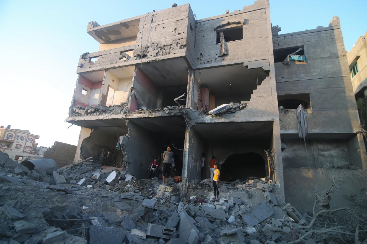 Palestinians stand by a building destroyed in an Israeli airstrike in the Rafah border, Gaza Strip (Copyright 2023 The Associated Press. All rights reserved.)