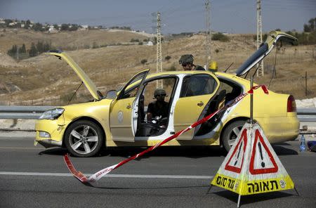 Israeli police explosives experts inspect a taxi at the scene of what police said was an attempted ramming attack near the West Bank Jewish settlement of Kfar Adumim November 22, 2015. REUTERS/Ronen Zvulun