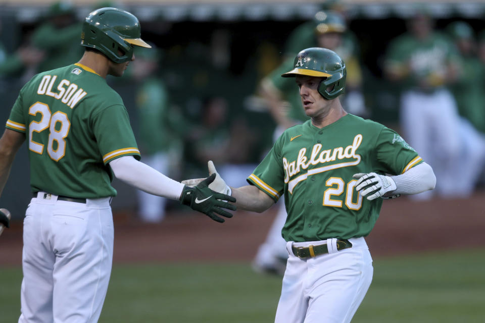Oakland Athletics' Mark Canha, right, is congratulated by Matt Olson after scoring on a single by Matt Chapman against the Los Angeles Angels during the third inning of a baseball game in Oakland, Calif., Tuesday, June 15, 2021. (AP Photo/Jed Jacobsohn)