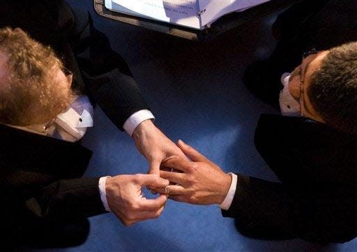 John Lewis, left, puts a wedding ring on the hand of Stuart Gaffney, both of San Francisco, at City Hall in San Francisco on June 17, 2008.