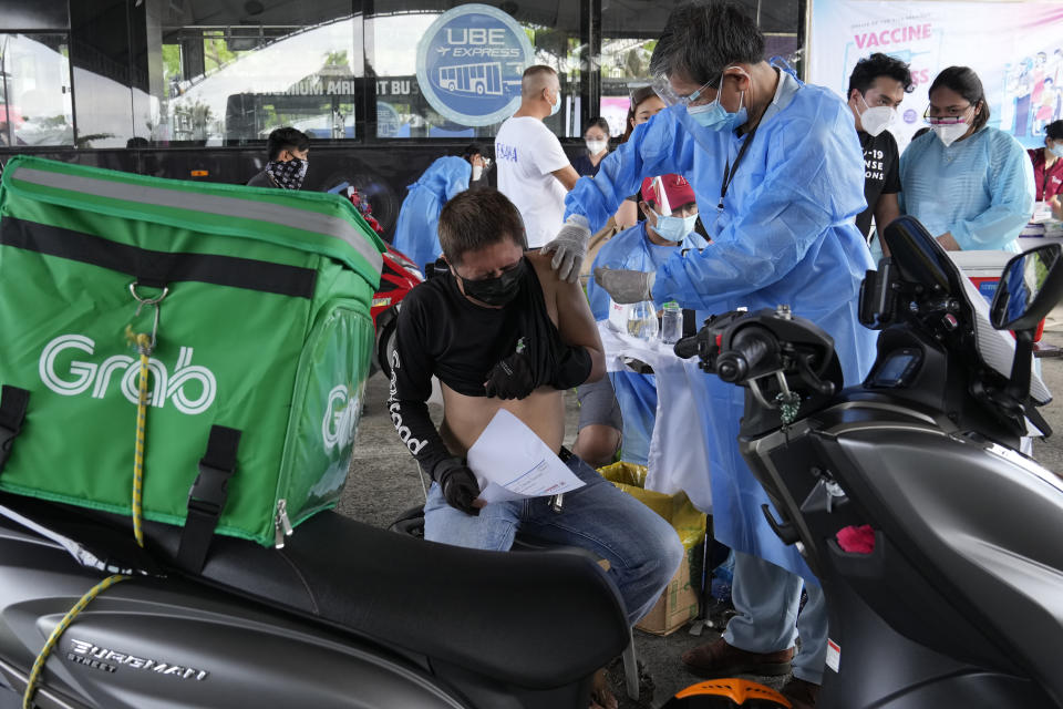 A motorcycle delivery driver is inoculated with China's Sinovac COVID-19 Vaccine at a drive-thru vaccination center in Manila, Philippines, Tuesday, June 22, 2021. The Philippine president has threatened to order the arrest of Filipinos who refuse COVID-19 vaccination and told them to leave the country for hard-hit countries like India and the United States if they would not cooperate with massive efforts to end the pandemic. (AP Photo/Aaron Favila)