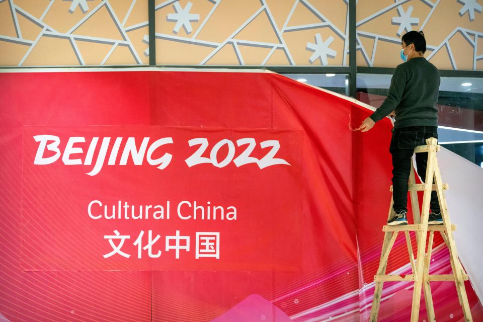 A worker takes down coverings around an exhibit on Chinese culture at a commercial plaza at the Winter Olympic Village in Beijing on Dec. 24, 2021. Organizers on Friday gave the media a look at parts of the athletes' Olympic Village for the 2022 Winter Olympics and Paralympics, which will be held beginning in February.