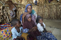 Aisha Ali, 40, sits with her children inside the hut where she found refuge from the floods in Darayami, northeastern Nigeria, Wednesday Oct. 26, 2022. When floodwaters reached her hut made of woven straw mats and raffia palms, she packed up what belongings she could and set off on foot with her eight youngest children. "While the flood was trying to destroy things, we were trying to save ourselves," she said. Four of her children perished. (AP Photo/Sunday Alamba)