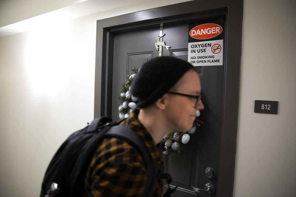 Noel Schroeder, with the nonprofit organization, "We Are Family DC," walks past a senior's door that warns of oxygen in use, as she delivered groceries to seniors in an apartment building, Saturday, March 21, 2020, in Washington. Seniors are being encouraged to stay in their homes due to the risk of the COVID-19 coronavirus. (AP Photo/Jacquelyn Martin)