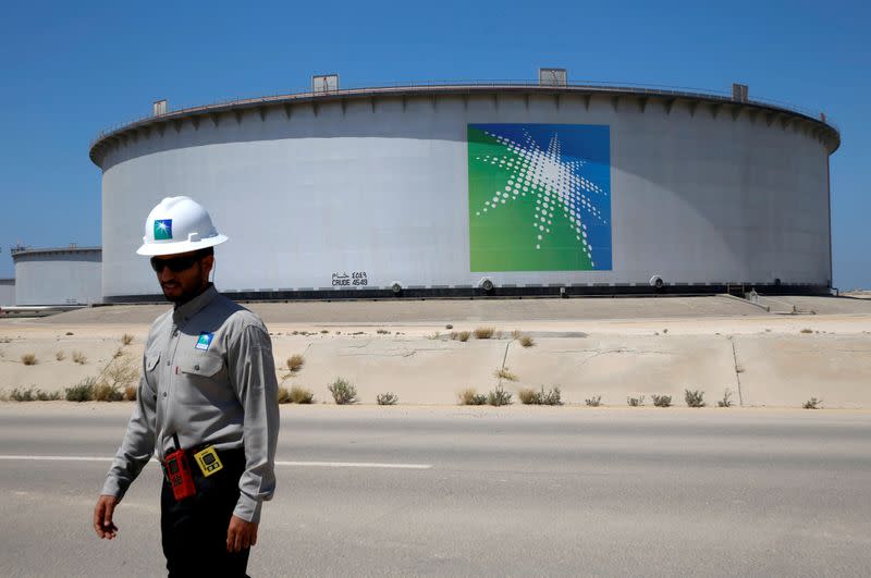 FILE PHOTO: An Aramco employee walks near an oil tank at Saudi Aramco's Ras Tanura oil refinery and oil terminal