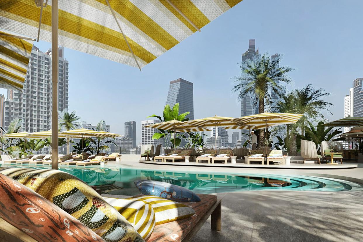 rooftop pool with yellow stripped umbrellas next to towering skyscrapers in Bangkok