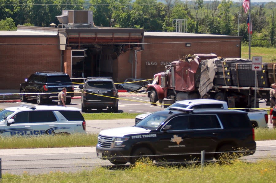 Emergency personnel work at the scene after an 18-wheeler crashed into the Texas Department of Public Safety Office in Brenham, Texas, Friday, April 12, 2024. A suspect is in custody in connection to a commercial vehicle crash at the Texas Department of Public Safety office in the rural town west of Houston. Texas DPS officials say multiple injuries were reported in the crash. (AP Photo/Lekan Oyekanmi)