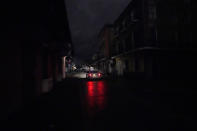 A passing car's headlights illuminate a darkened Bourbon Street in the French Quarter of New Orleans, Wednesday, Oct. 28, 2020. Hurricane Zeta passed through Wednesday leaving much of the city and metro area without power. (AP Photo/Gerald Herbert)