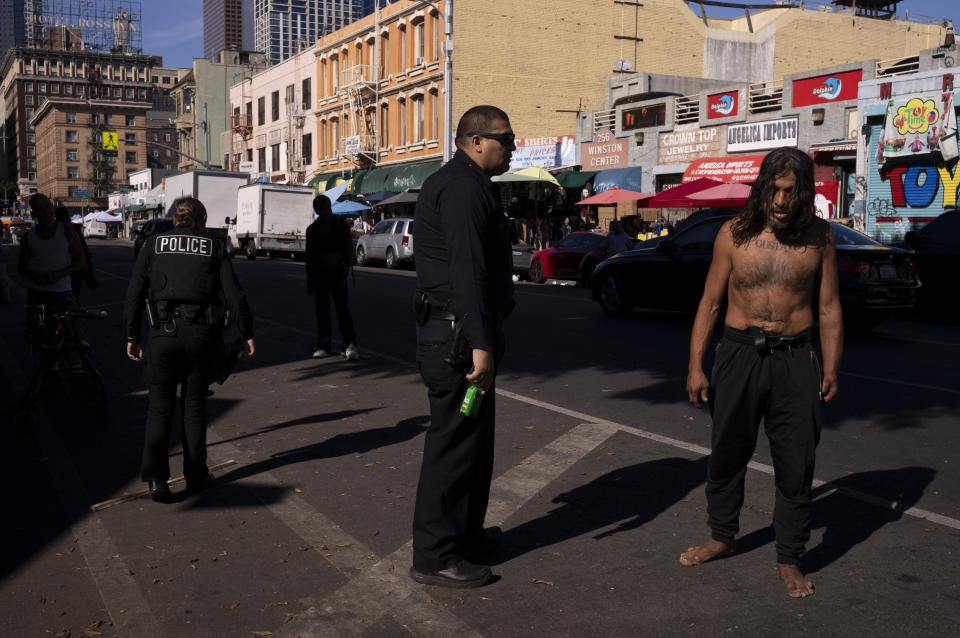 A police officer with a Taser breaks up a fight between two homeless people in downtown Los Angeles, Wednesday, Nov. 22, 2023. Downtown's Skid Row neighborhood remains the epicenter of the crisis, where tents extend for blocks and unconscious people can be found splayed on sidewalks and slumped in doorways. Some streets have been transformed into parking lots for rusted, parked RVs. (AP Photo/Jae C. Hong)