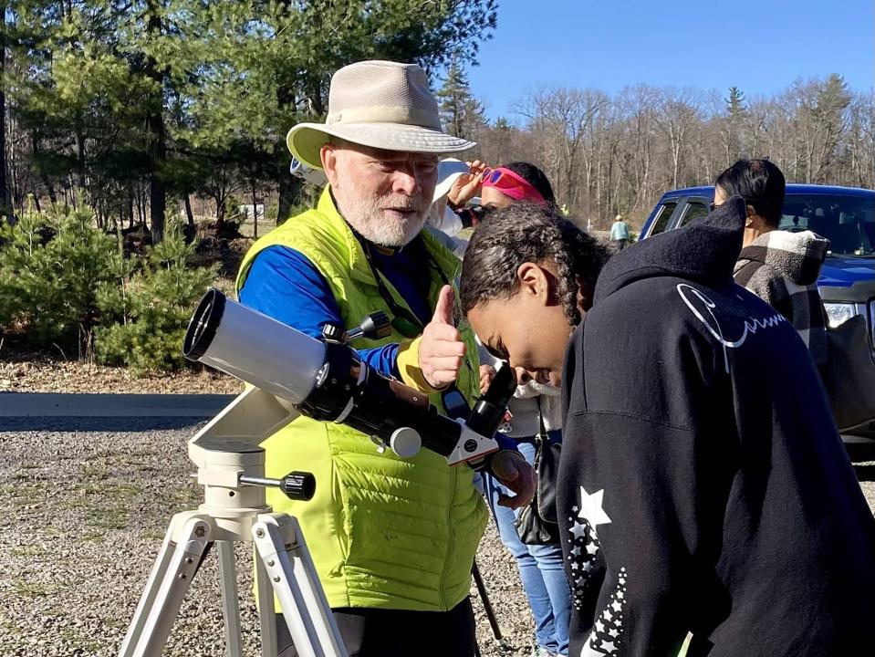 Corinne Wyatt, 15, of Richmond, Virginia, peers through a telescope operated by Val Szwarc, 70, of Ridgway, Colorado, on Sunday, April 7, 2024, at the Oil Region Astronomical Society, located southeast of Oil City in Venango County, Pennsylvania. Szwarc, an advocate in the dark sky movement which seeks to protect night skies from light pollution, traveled to Venango County for the eclipse, with his wife, Laura McAlevy, an Oil City native. Wyatt traveled to the region with her family to see the total eclipse. Szwarc had the telescope trained on sunspots.