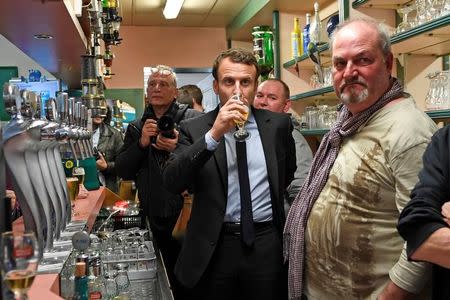 Emmanuel Macron, head of the political movement En Marche !, or Onwards !, and candidate for the 2017 French presidential election, drinks a beer behind the bar counter while meeting with residents at a cafe in Bully-les-Mines, France, April 26, 2017. REUTERS/Eric Feferberg/Pool