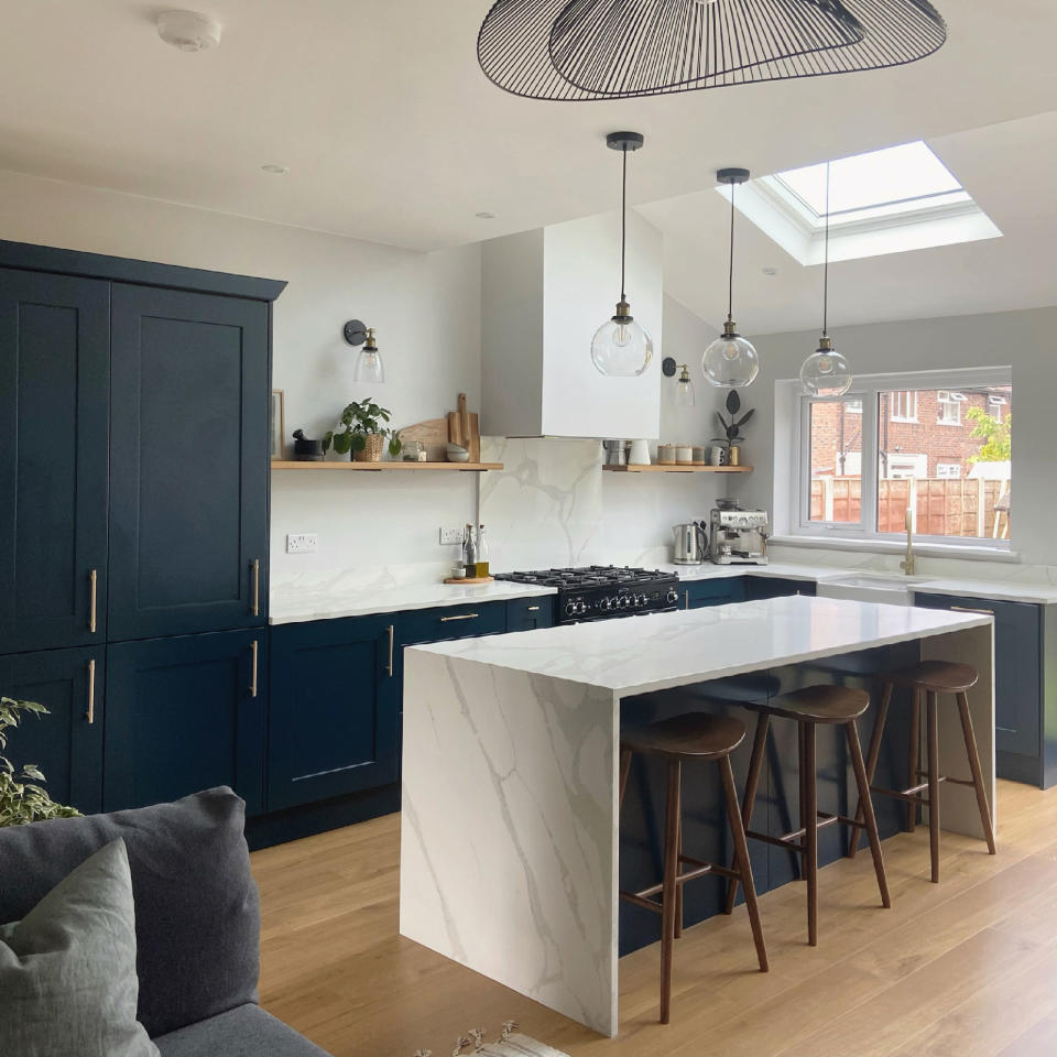 Kitchen with blue units and marble-effect waterfall work surface on breakfast bar