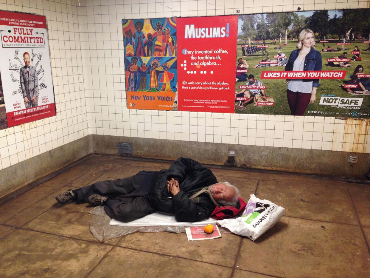 In this March 30, 2016 photo, a homeless man sleeps on a floor of the F train, East Broadway subway station in Manhattan's Chinatown, in New York. 