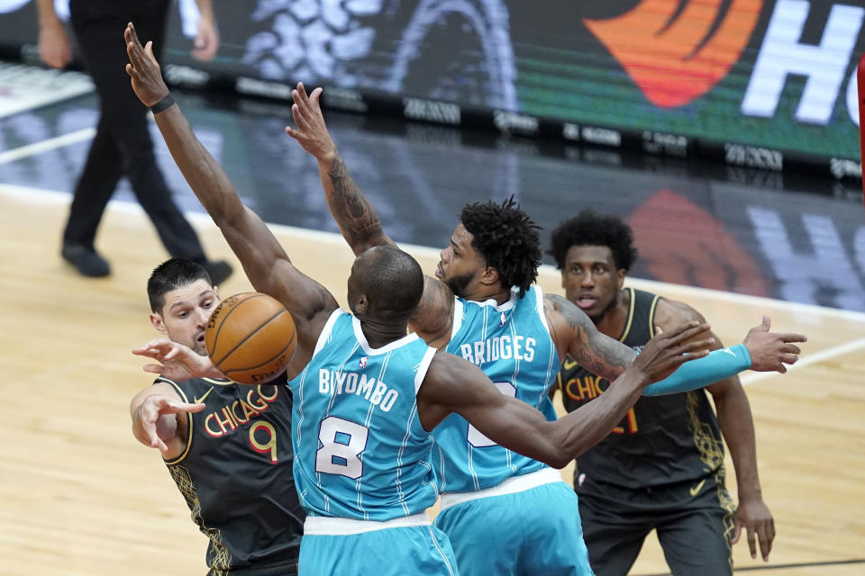 Charlotte Hornets' Bismack Biyombo (8) and Miles Bridges (0) pressure Chicago Bulls' Nikola Vucevic (9) who passes the ball during the first half of an NBA basketball game Thursday, April 22, 2021, in Chicago. (AP Photo/Charles Rex Arbogast)