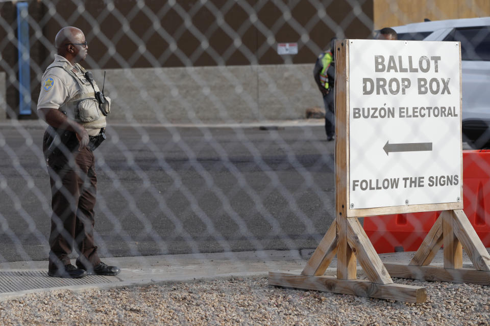 A security guard watches over a ballot drop box in Phoenix on Monday. 