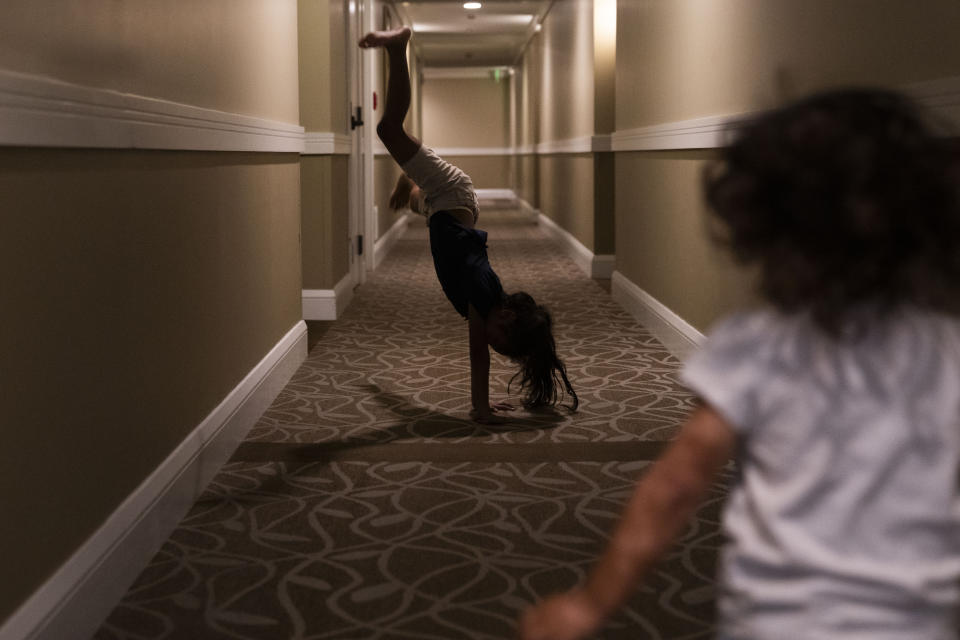 Zaevah Erickson-Castaneto, 7, does a cartwheel while being followed by sister Mahina, 2, as they return to their room at the Honua Kai Resort & Spa, where the family currently lives after being displaced by the August wildfire Friday, Dec. 8, 2023, in the Kaanapali area of Lahaina, Hawaii. The children's great-grandmother Louise Abihai was among the victims in the deadliest U.S. wildfire in more than a century that took the lives of at least 100 people and destroyed most of the historic town of Lahaina. (AP Photo/Lindsey Wasson)