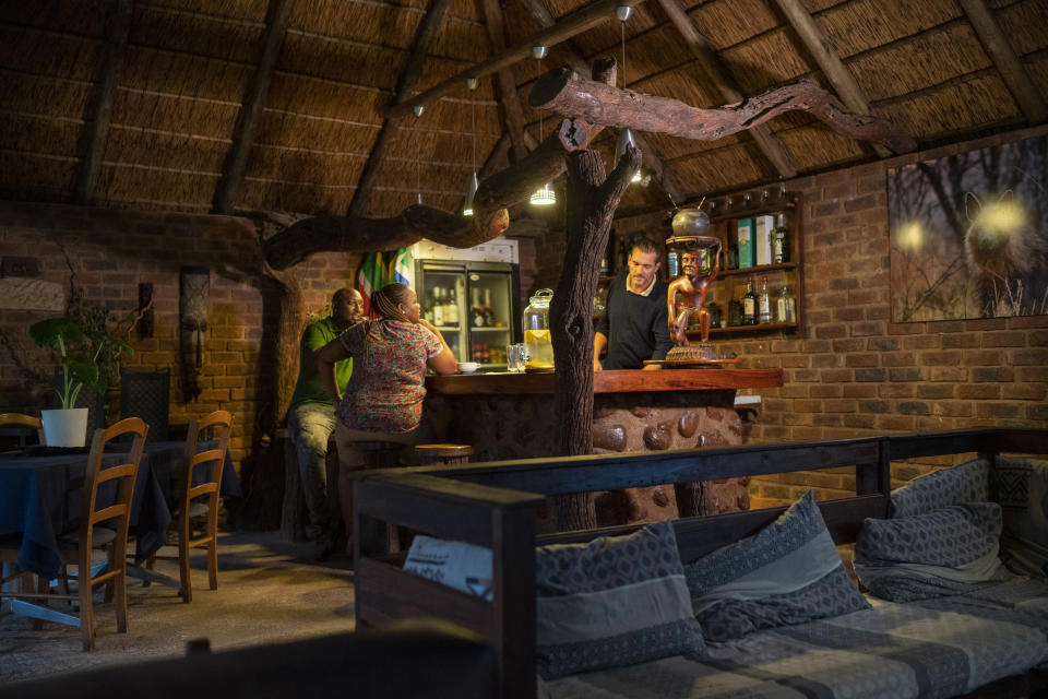 Tebogo Masiu, left and Smagele Twala sit at the bar of the Tamboti Bush Lodge in the Dinokeng game reserve near Hammanskraal, South Africa Saturday Dec. 4, 2021. Recent travel bans imposed on South Africa and neighboring countries as a result of the discovery of the omicron variant in southern Africa have hammered the country’s safari business, already hard hit by the pandemic. (AP Photo/Jerome Delay)