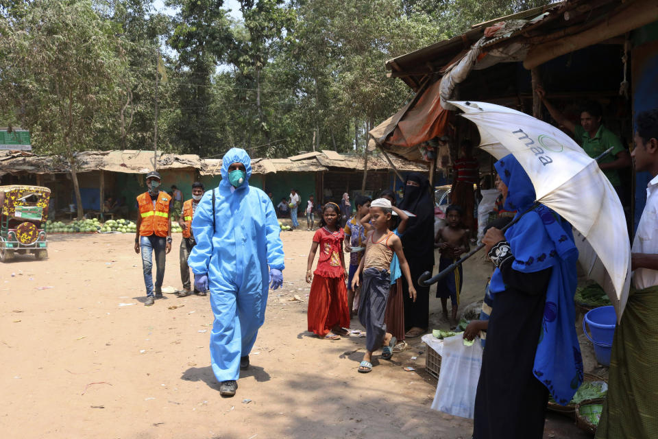 FILE - In this April 15, 2020, file photo, a health worker from an aid organization walks wearing a hazmat suit at the Kutupalong Rohingya refugee camp in Cox's Bazar, Bangladesh. Authorities on Thursday, May 14, 2020 reported the first coronavirus case in the crowded camps for Rohingya refugees in southern Bangladesh, where more than 1 million refugees have been sheltered, a Bangladeshi official and the United Nations said. (AP Photo/Shafiqur Rahman, File)