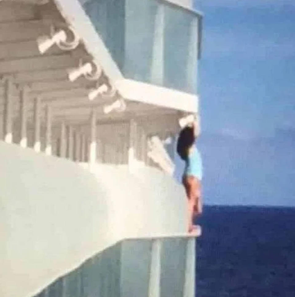 A passenger stands on the ledge of a Royal Caribbean Cruises ship.