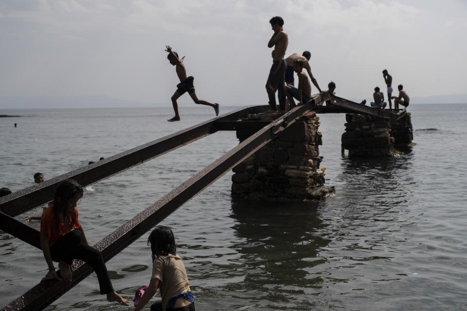 Migrants play into the sea near Mytilene town, on the northeastern island of Lesbos, Greece, Tuesday, Sept. 15, 2020. Just over 6% of the 12,500 people left homeless last week by the fire that destroyed Greece's biggest camp for refugees and migrants have been rehoused in a new temporary facility under construction on the island of Lesbos. (AP Photo/Petros Giannakouris)