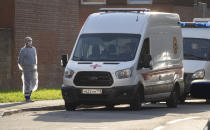 A medical worker wearing protective gear, waits near ambulances standing in line to deliver patients suspected of being infected with coronavirus to a hospital for COVID-19 patients in St.Petersburg, Russia, Thursday, Oct. 1, 2020. The number of daily new cases started to rapidly grow this month in Russia, which had earlier lifted most of the virus-related restrictions and resumed air traffic with several countries. (AP Photo/Dmitri Lovetsky)