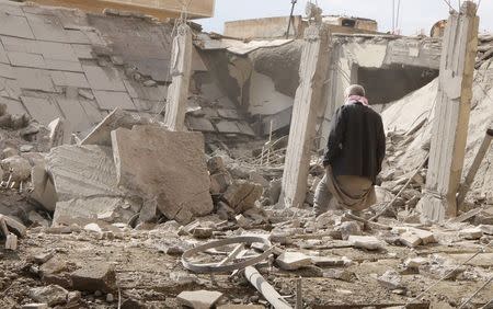 A man makes his way through rubble at a site hit by what activists said were airstrikes by forces loyal to Syria's President Bashar al-Assad in Raqqa, eastern Syria, which is controlled by the Islamic State November 27, 2014. REUTERS/Nour Fourat