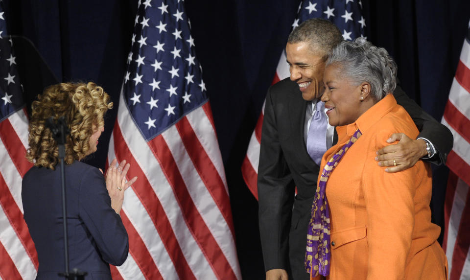 President Barack Obama hugs Democratic strategist Donna Brazile, right, as Democratic National Committee Chairwoman Rep. Debbie Wasserman-Schultz, D-Fla., watches at left, as Obama arrived to speak at the Democratic National Committee Winter Meeting in Washington, Friday, Feb. 28, 2014. (AP Photo/Susan Walsh)