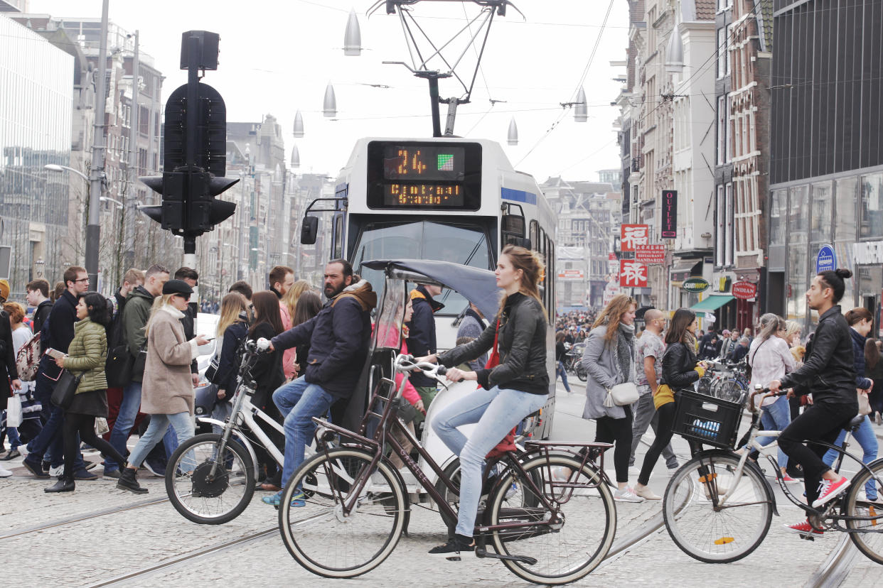 AMSTERDAM,NETHERLANDS - APRIL 14: People walking and cycling cross the Rokin aveneu next Dam square donwtown in Amsterdam,Netherlands.