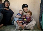 BOLDOC, AFGHANISTAN - NOVEMBER 23: (SPAIN OUT, FRANCE OUT, AFP OUT) Lance Corporal Luz Lopez, 21, a US Marine with the FET (Female Engagement Team) 1st Battalion 8th Marines, Regimental Combat team II plays with Afghan babies during a village medical outreach on November 23, 2010 in Boldoc, in Helmand province , Afghanistan. There are 48 women presently working along the volatile front lines of the war in Afghanistan deployed as the second Female Engagement team participating in a more active role, gaining access where men can't. The women, many who volunteer for the 6.5 month deployment take a 10 week course at Camp Pendleton in California where they are trained for any possible situation, including learning Afghan customs and basic Pashtun language. (Photo by Paula Bronstein/Getty Images)