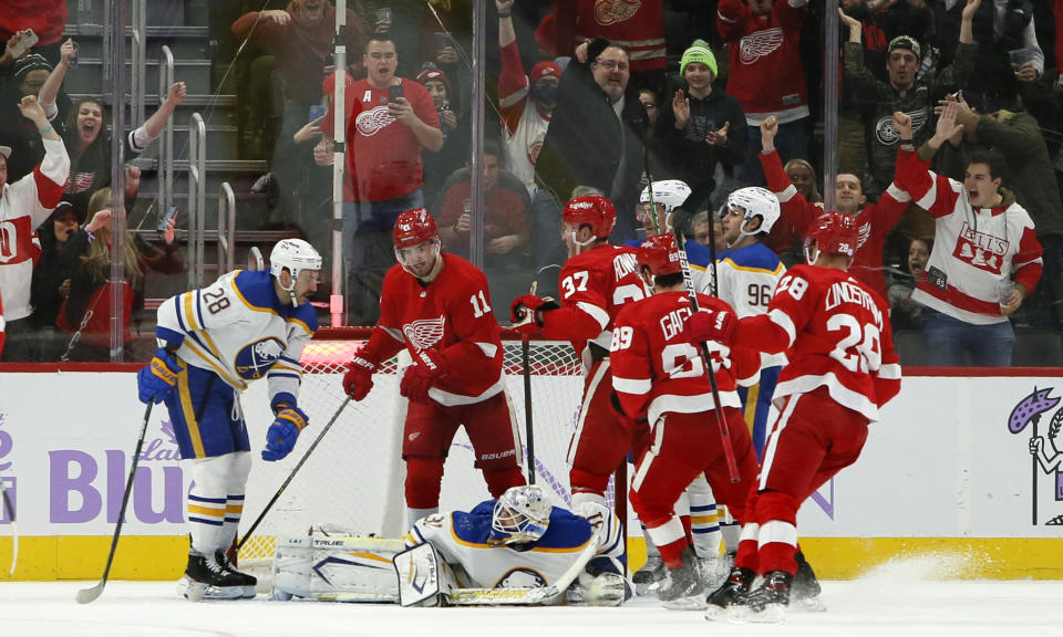 Detroit Red Wings right wing Carter Rowney (37) celebrates his goal with right wing Filip Zadina (11) with Buffalo Sabres goaltender Dustin Tokarski (31) on the ice and defender center Zemgus Girgensons (28) during the second period of an NHL hockey game Saturday, Nov. 27, 2021, in Detroit. (AP Photo/Duane Burleson)