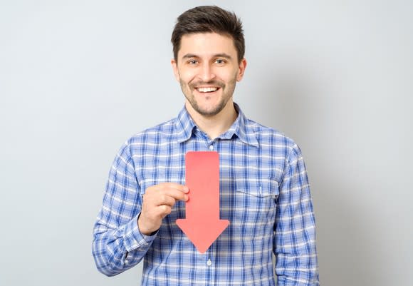 Man smiling while holding arrow that's pointing down