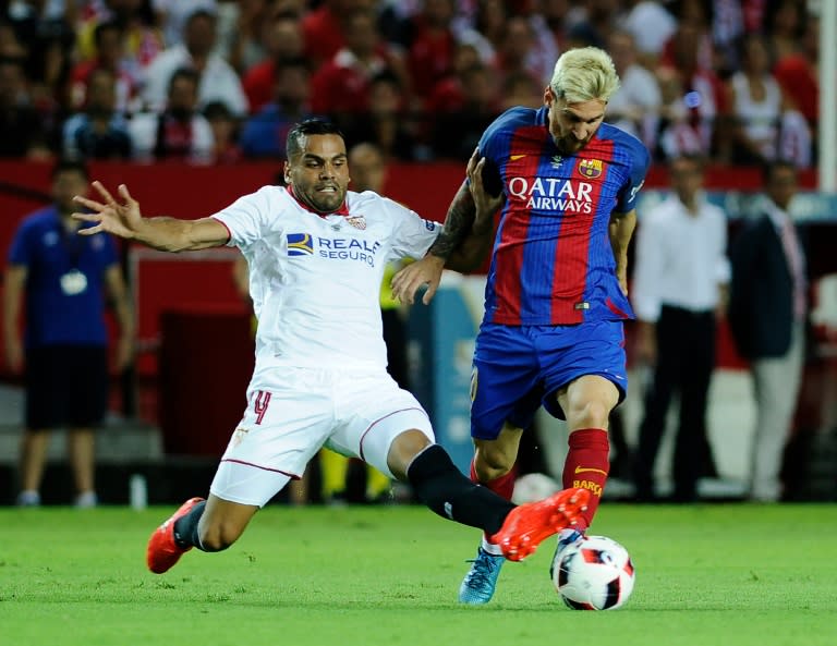 Barcelona's Lionel Messi (R) is challenged by Sevilla defender Gabriel Mercado during the Supercup first-leg match