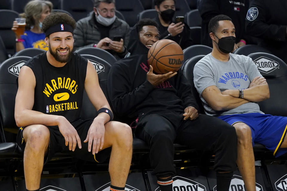 Miami Heat's Kyle Lowry, middle, smiles while sitting between Golden State Warriors' Klay Thompson, left, and Warriors assistant coach and director of player development Jama Mahlalela before an NBA basketball game between the Warriors and the Heat in San Francisco, Monday, Jan. 3, 2022. Coach Steve Kerr and his assistants met during the summer along with Stephen Curry and Draymond Green to review how they might practice more efficiently and with greater focus, and the resulting “Golden Hour” has meant so much to Golden State’s success so far. (AP Photo/Jeff Chiu)