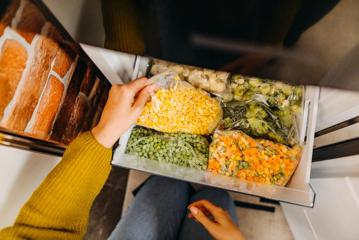 Woman's hands pulling frozen vegetables out of a freezer