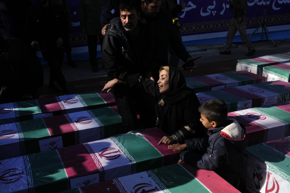 A woman mourns over the flag-draped coffin of her loved one who was killed in Wednesday's bomb explosion, during the victims funeral ceremony in the city of Kerman about 510 miles (820 kms) southeast of the capital Tehran, Iran, Friday, Jan. 5, 2024. Iran on Friday mourned those slain in an Islamic State group-claimed suicide bombing targeting a commemoration for a general slain in a U.S. drone strike in 2020, as the death toll in the attack rose to at least 89. (AP Photo/Vahid Salemi)