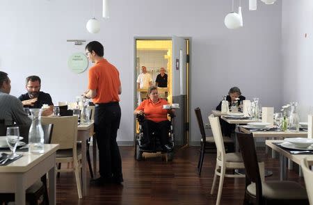 A waiter takes orders from guests, while waitress Maria Kecskemeti (in wheelchair) delivers two cups of soup in Izlelo, a restaurant in Szekszard, south of Budapest, September 22, 2014. REUTERS/Bernadett Szabo