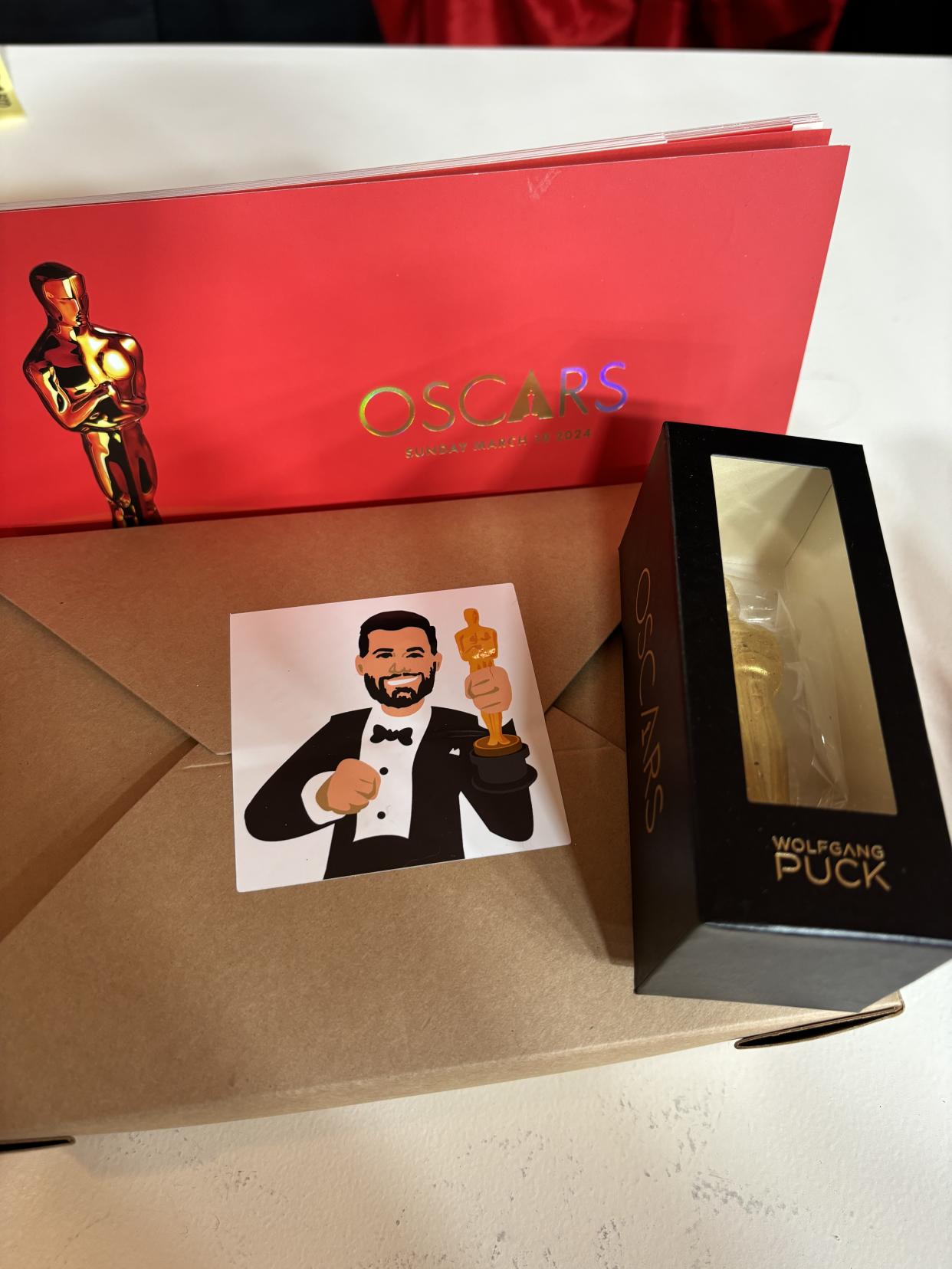 The snack box provided underneath each guest seat, the printed Oscars program, and a chocolate Oscar in a box.