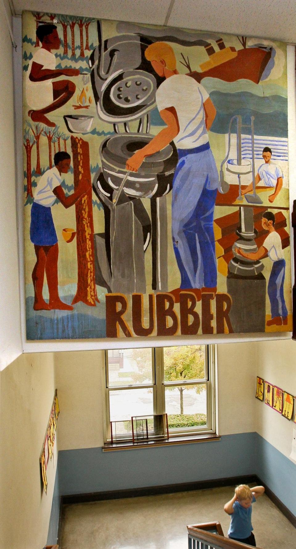 A student at Lawndale Elementary School walks  beneath a 1947 mural depicting the Akron rubber industry in 2011. The Kenmore school closed in 2016.