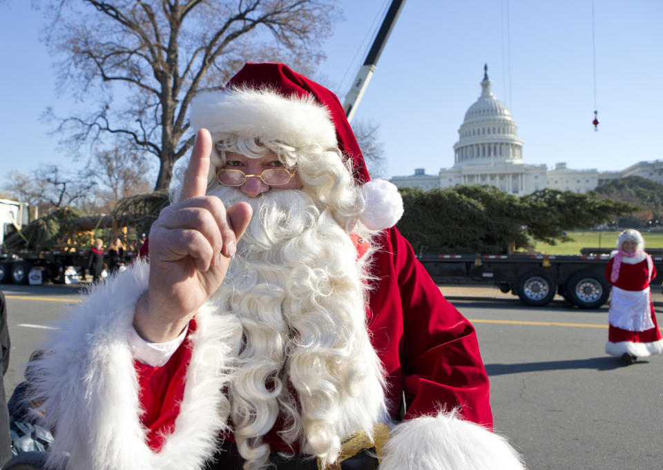 Santa Claus and Mrs. Claus, portrayed by Gerald and Twila Morris of Meeker, Colo., greet visitors on Capitol Hill in Washington, Monday, Nov. 26, 2012, as the 2012 Capitol Christmas Tree, a 73-foot Engelmann Spruce from the White River National Forest, near Meeker, Colo. rear, on truck, arrives. (AP Photo/J. Scott Applewhite)