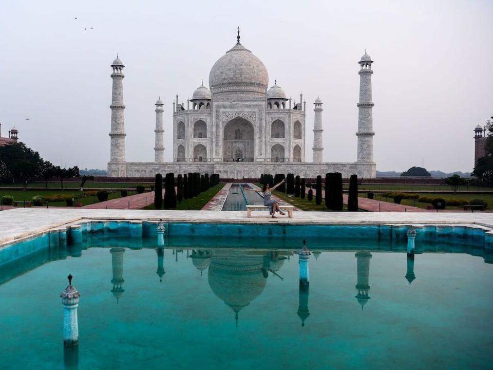 A single tourist takes a picture at the empty Taj Mahal.