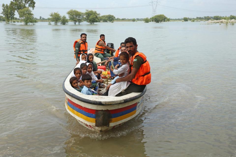 Rescue workers use a boat to drop children back home after school in a flood hit area following heavy monsoon rains in Dera Ghazi Khan (AFP via Getty Images)