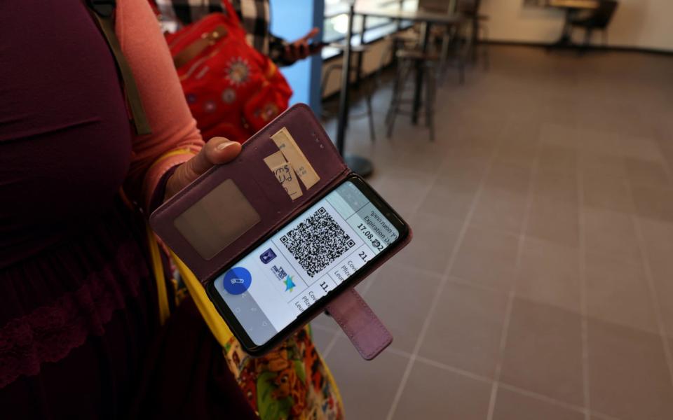 A woman shows her Covid vaccination status on her mobile phone at a gym where a "Green Badge" is required to enter, as Israel reopens -  RONEN ZVULUN /reuters